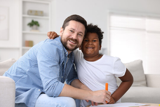 Adoption. Father and his son drawing together at table indoors