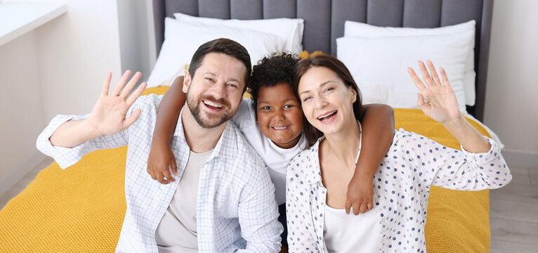 Adoption. Happy parents and their son on bed at home - Powered by Adobe
