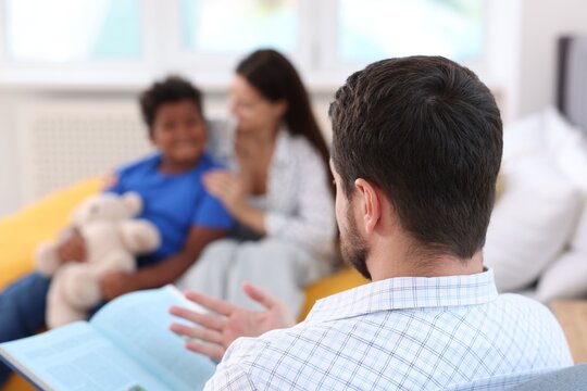 Father reading story to his family at home, selective focus