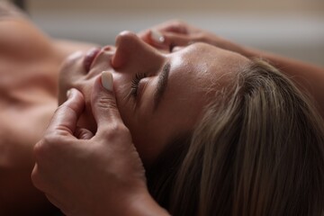 Beautiful woman receiving facial massage, closeup view