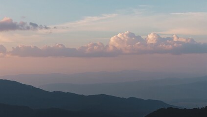 Obraz premium Layered mountains at sunset, with soft clouds and a peaceful, dreamy atmosphere. Calm, and majestic.
