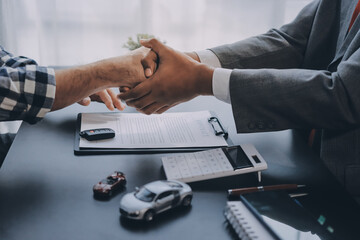 Fototapeta premium Car salesman gave the keys to the customers who signed the purchase contract legally, Successful completion of car sales, Purchase contract and key delivery.