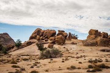 Massive granite rock formations in Tafraout Morocco desert with sparse vegetation, dramatic sky and rugged Anti-Atlas mountain landscape