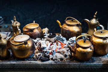 Brass pots on hot coals for traditional tea brewing