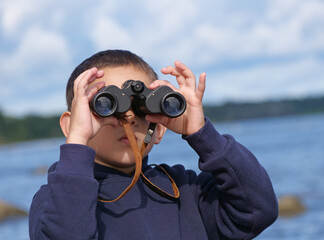 Close-up of child using binoculars on the sea beach