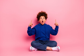 Charming young boy in vibrant blue hoodie making expressive gestures against a vivid pink background for lifestyle concept.