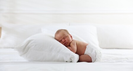 Cute newborn baby sleeping on bed indoors