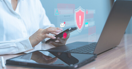 Businesswoman holding smartphone with digital red shield and warning alert symbolizing mobile data...