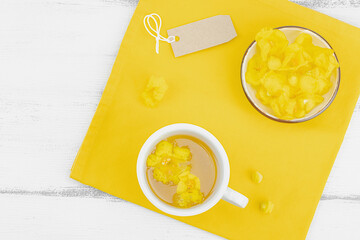 Cup of herbal tea with mullein flowers and leaves on neutral wooden background. Natural light