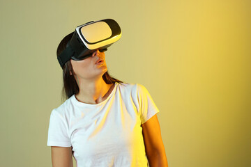 Emotional woman using virtual reality headset in neon lights against color background