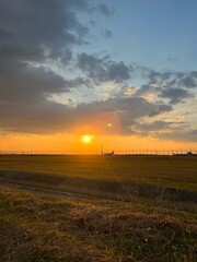 Sunset over golden fields with fence and colorful sky, A golden sunset over a grassy prairie with a rustic wooden fence,  Sunset over a barbed wire fence and rural field, golden light.
