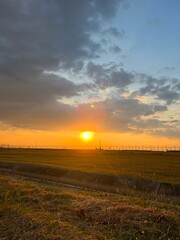 Sunset over golden fields with fence and colorful sky, A golden sunset over a grassy prairie with a rustic wooden fence,  Sunset over a barbed wire fence and rural field, golden light.
