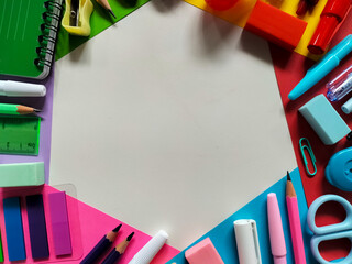 Assortment of school supplies arranged on a colorful background. 
