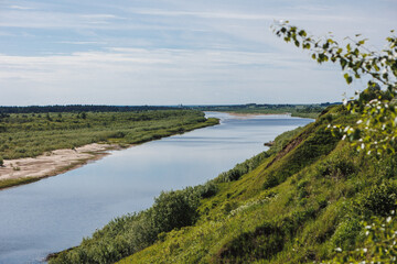 A tranquil view of a winding river bordered by vibrant greenery under a clear sky, capturing the beauty of nature in harmony.