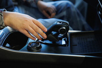 A close-up view of a hand on a modern car gear shift, showcasing sleek automotive design and interior features.
