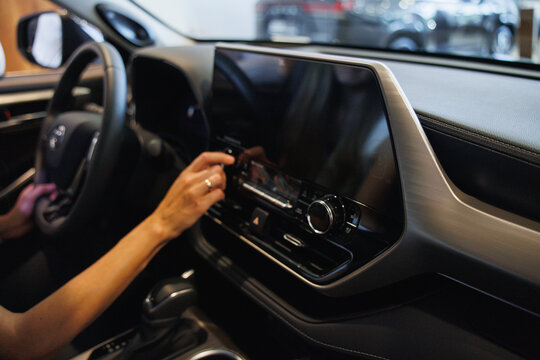 Close-up of a person using a touchscreen in a contemporary car interior, showcasing advanced technology and sleek design.
