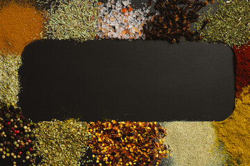 Frame made with different spices on dark background, flat lay. Space for text