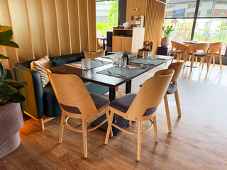 Restaurant interior with wooden chairs, sofa seating, and table set for guests. Dining, hospitality, and social atmosphere arranged for comfort, leisure, and service.