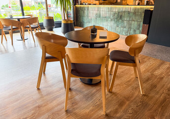 Round dining table with chairs near large window overlooking outdoor view. Hospitality, leisure, and social atmosphere for guests enjoying restaurant setting.