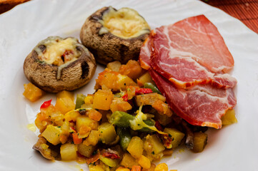 Gourmet Dish Featuring Grilled Mushrooms with Cheese Accompanied by Roasted Vegetables and Cured Meats on Elegant White Plate