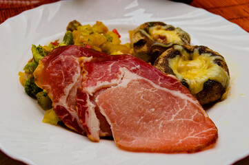 Gourmet Dish Featuring Succulent Slices of Ham with Stuffed Mushrooms and Vibrant Vegetables on Elegant White Plate