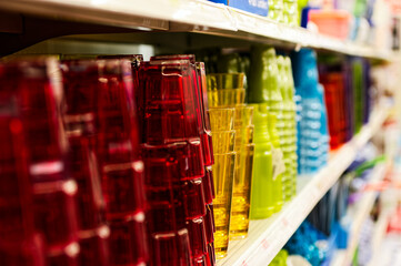 Colorful Plastic Cups and Glasses Displayed on Store Shelf in Vibrant Array of Red, Yellow, Green, and Blue for Kitchenware Shopping Experience