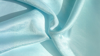 A close-up of luxurious, flowing light blue silk fabric with soft folds and elegant highlights. This serene texture evokes calm, sophistication, and delicate beauty, perfect for fashion, beauty, or ca