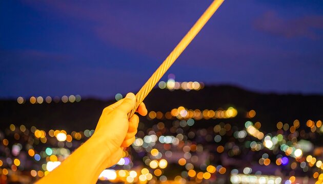 Hand holding a rope at night over a city