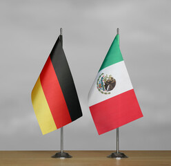 Tabletop flags of Germany and Mexico on stands on a gray blurred background