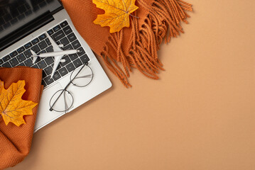 Flatlay showcasing a laptop adorned by autumn-themed objects including leaves and a scarf, symbolizing seasonal work and travel vibes