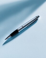 A silver-toned ballpoint pen lies diagonally on a light-blue surface, catching the light