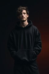 Fototapeta premium An expressive portrait of a handsome young man in a minimalist black hoodie, capturing a blend of casual style and quiet contemplation, against a dramatic dark backdrop