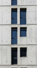 Fototapeta premium A modern concrete building facade, featuring a repeating pattern of rectangular windows and doors, displaying a structured and minimalist aesthetic.