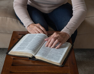 Fototapeta premium Elderly Woman's Hand Pointing to Bible Verse