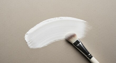 A delicate white paint stroke rests upon a neutral backdrop, accompanied by a matching paintbrush.
