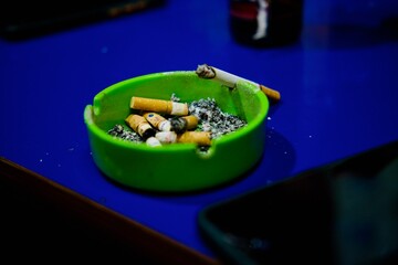 Cigarette and ashtray on blue background