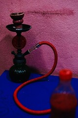 Hookah on a table with blue table and pink wall background