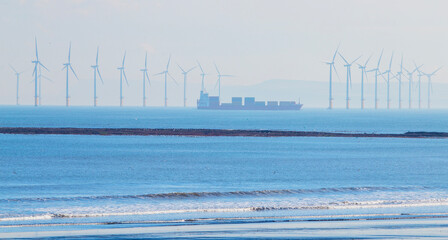 Fototapeta premium An offshore wind farm in the North Sea off the Yorkshire coast with a container ship making way through it