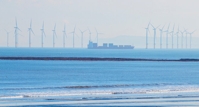 An offshore wind farm in the North Sea off the Yorkshire coast with a container ship making way through it
