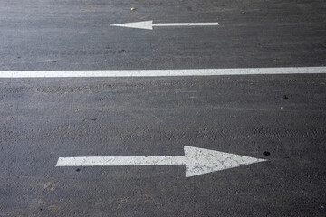 White directional arrows painted on asphalt, symbol of choice, opposite directions, decision-making...