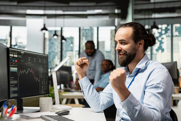 Happy day trader in officer celebrating after making successful market prediction and making profit. Brokerage company employee enjoying success after portfolio value increases, earning high returns