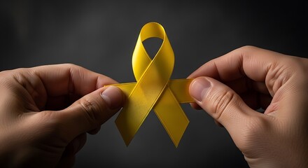 Yellow ribbon held by hands for support awareness campaign and solidarity concept