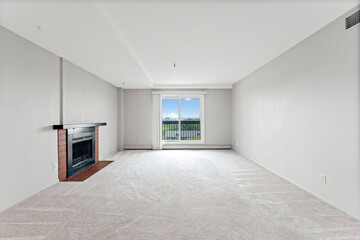 Large, empty living room with a fireplace and a window