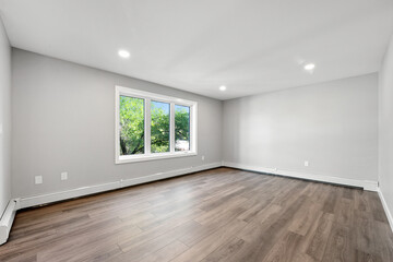 Large, empty room with a window and a white wall