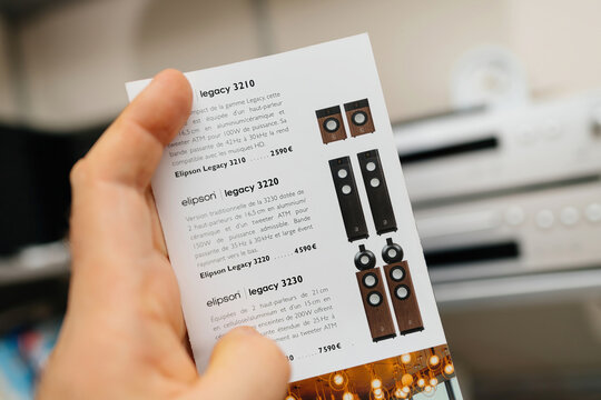 Hamburg, Germany - Mar 27, 2023: POV male hand reading fluer featuring Elipson Legaxy 3220 3210 3230 luxury floorstanding speakers with hi-fi background