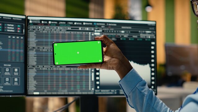 Close up of portfolio manager using mockup smartphone to watch trading educational content. Hedge fund professional in office learns new trading strategies from video lesson on green screen phone