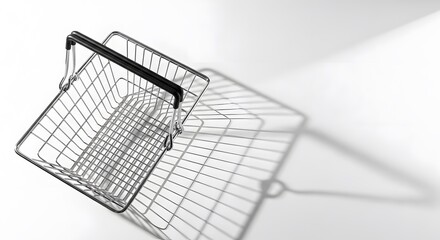 A metal shopping basket casts a long shadow on a white surface, creating a minimalist and abstract composition.