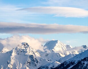 Fototapeta premium Majestic snow-capped peaks rise through a soft, ethereal sky blanketed by layered clouds.