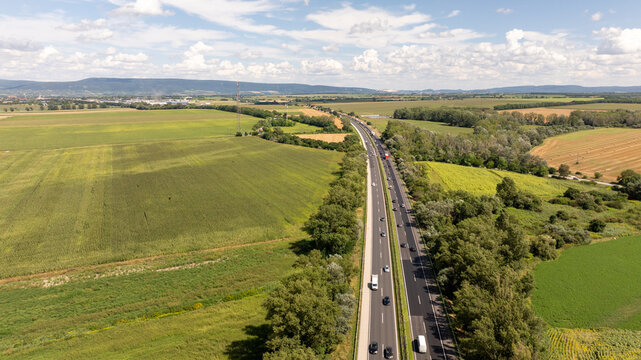 Aerial view of traffic flowing on the m1 motorway near tata, Hungary, cutting through a picturesque landscape of agricultural fields and trees
