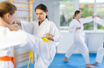 Young girl and female adversary got into fight during kickboxing training session. Opponent punches enemy with feet and hands, using all strength, courage